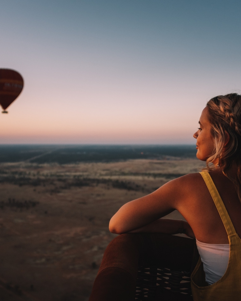 A visitor looks out over the Red Centre landscape while on a hot air balloon with Outback Ballooning © Tourism NT, Laura Bell