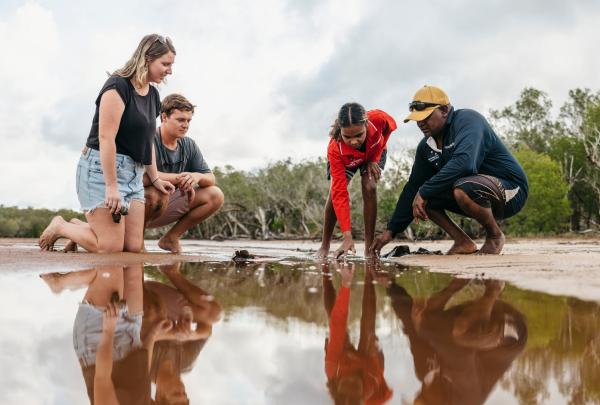 Indigenous tour guides and couple kneeling down to view a tidal pool, Southern Cross Cultural Walk, Cygnet, Western Australia © Tourism Australia