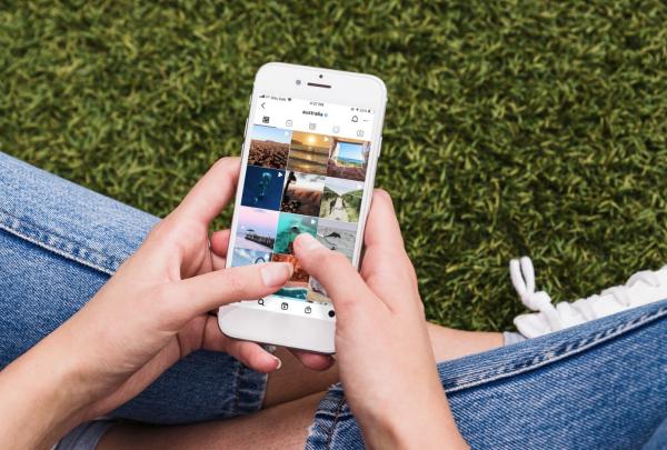 Person sitting down cross-legged, looking at Instagram on their phone © Tourism Australia