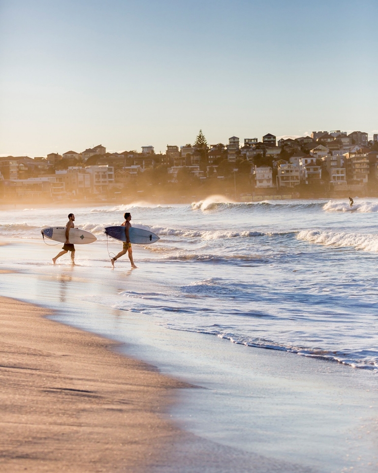 Two surfers running with their boards, about to enter the water on Bondi Beach, Sydney, New South Wales © Daniel Boud, Destination NSW